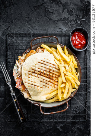 Doner kebab sandwich in grilled pita bread with vegetables and chicken meat. Black background. Top view 98122677