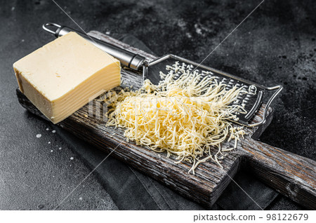 Grated cheese for cooking on a cutting board . Black background. Top view 98122679