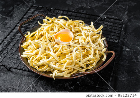 Dry spaetzle egg noodle in a steel tray. Black background. Top view 98122714