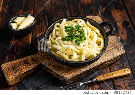 German Spaetzle egg Noodles with Butter and Parsley in a skillet. Wooden background. Top view German Spaetzle egg Noodles with Butter and Parsley in a skillet. Wooden background. Top view 98122725