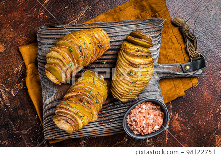 Roasted Hasselback Potato with Fresh thyme and rosemary. Dark background. Top view Roasted Hasselback Potato with Fresh thyme and rosemary. Dark background. Top view 98122751