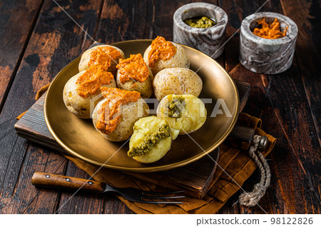 Canary Islands dish Papas Arrugadas wrinkly salty potatoes with and Mojo picon red spicy sauce. Wooden background. Top view 98122826