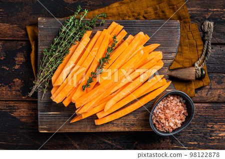 Sweet potatoes on a cutting board, fresh batata french fries ready for cooking. Wooden background. Top view Sweet potatoes on a cutting board, fresh batata french fries ready for cooking. Wooden background. Top view 98122878
