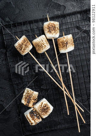 BBQ Grilled Marshmallow on the sticks. Black background. Top view BBQ Grilled Marshmallow on the sticks. Black background. Top view 98122911
