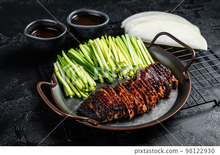 Peking Duck served with cucumber, green onions, and roasted wheaten chinese pancakes with sauce Hoysin. Black background. Top view 98122930