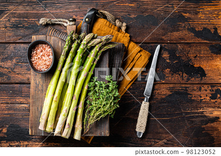 Bunch of Raw green asparagus on a wooden cutting board. Wooden background. Top view Bunch of Raw green asparagus on a wooden cutting board. Wooden background. Top view 98123052