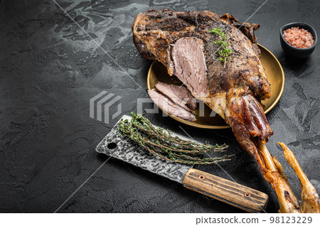 Christmas dish - Roast lamb leg meat with spices and thyme on a plate. Black background. Top view. Copy space Christmas dish - Roast lamb leg meat with spices and thyme on a plate. Black background. Top view. Copy space 98123229