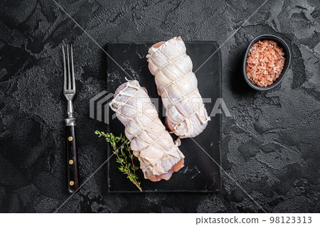 Cooking raw chicken rolls stuffed with cheese and ham. Black background. Top view 98123313