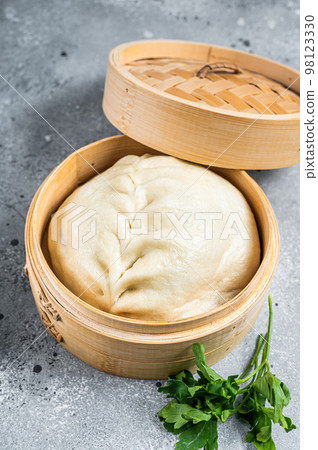 Pyanse steamed bun in a Bamboo steamer, korean street food. Gray background. Top view 98123330