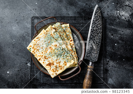 Gozleme Turkish flatbread with greens and cheese. Black background. Top view Gozleme Turkish flatbread with greens and cheese. Black background. Top view 98123345