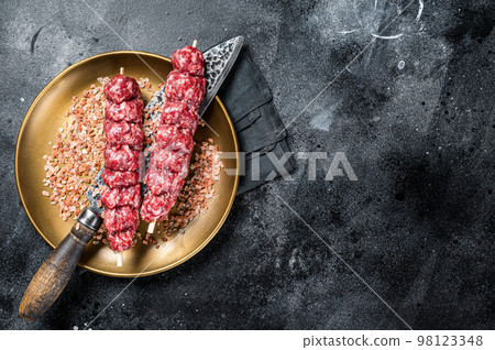 Raw kofta, kofte kebab Skewers with beef and lamb meat and spices. Black background. Top view. Copy space Raw kofta, kofte kebab Skewers with beef and lamb meat and spices. Black background. Top view. Copy space 98123348