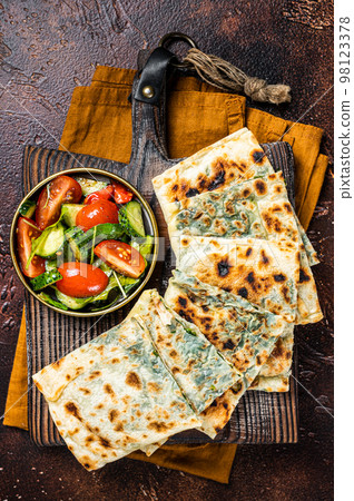 Freshly baked Turkish Gozleme, flatbread with greens and cheese. Dark background. Top view 98123378