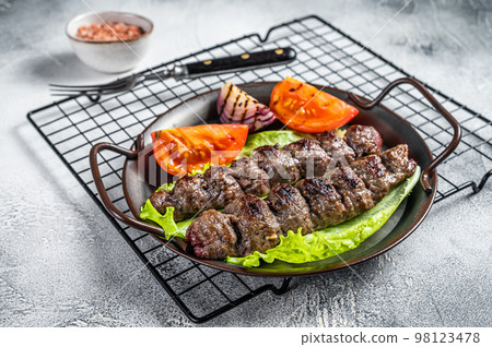 Grilled Adana kebab served with tomato, salad and onion. White background. Top view. Copy space 98123478