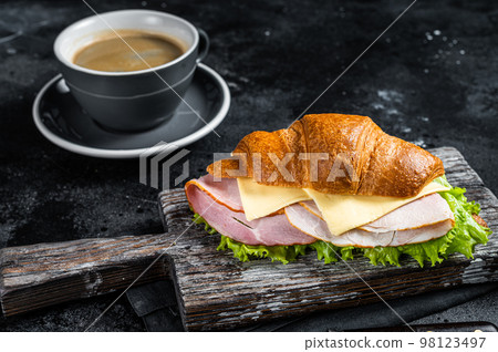 Croissant Club Sandwich with Ham and Cheese, cup of coffe. Black background. Top view 98123497
