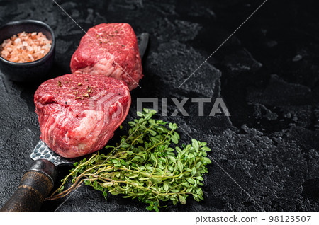 Fillet Mignon Beef steak, raw dry aged marble meat. Black background. Top view. Space for text 98123507