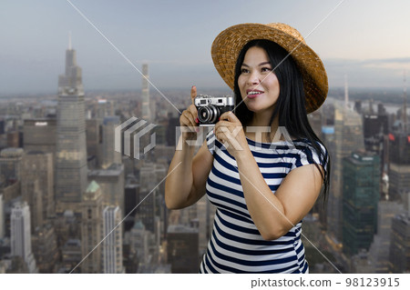 Happy young tourist korean woman aking a photo on vintage camera. Metropolis cityscape background. Happy young tourist korean woman aking a photo on vintage camera. Metropolis cityscape background. 98123915