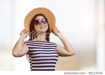 Portrait of happy young brunette woman wearing sunglasses and straw hat. Bright blurred background. Portrait of happy young brunette woman wearing sunglasses and straw hat. Bright blurred background. 98123926