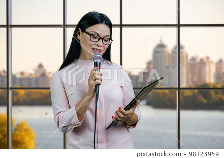 Business woman with a microphone and clipboard. Checkered windows background. Business woman with a microphone and clipboard. Checkered windows background. 98123959