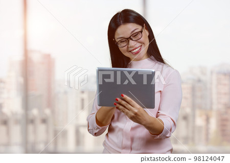 Portrait of smiling young asian businesswoman with glasses. Indoor windows bacgkground. Portrait of smiling young asian businesswoman with glasses. Indoor windows bacgkground. 98124047