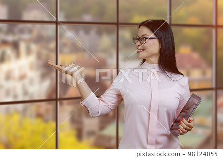 Young asian businesswoman holding tablet pc and showing copy space. Autumn streetscape background. Young asian businesswoman holding tablet pc and showing copy space. Autumn streetscape background. 98124055