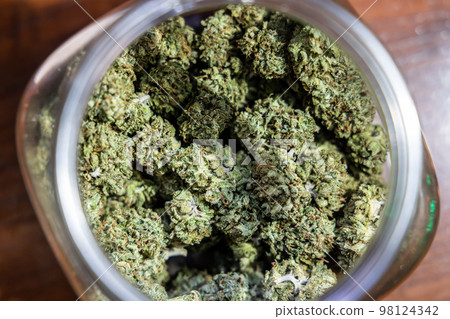 Closeup selective focus on processed cannabis flower in jar ready to be rolled into cigarette 98124342