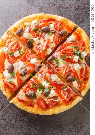 Tasty Greek pizza on a thin pastry base sliced closeup on the wooden board. Vertical top view Tasty Greek pizza on a thin pastry base sliced closeup on the wooden board. Vertical top view 98124500