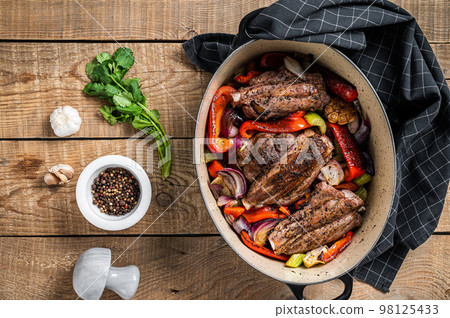 Roasted slow cooked lamb shanks with vegetables and herbs. Wooden background. Top view 98125433
