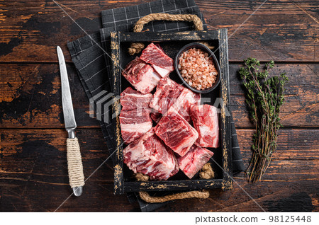 Uncooked Raw diced cubes of lamb meat in wooden tray with salt and thyme. Wooden background. Top view 98125448