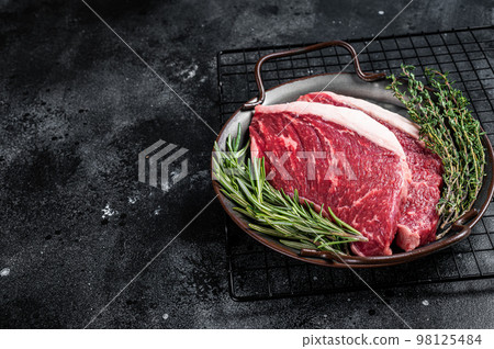 Raw top sirloin or Picanha beef meat steak in a steel tray. Black wooden background. Top view. Copy space Raw top sirloin or Picanha beef meat steak in a steel tray. Black wooden background. Top view. Copy space 98125484