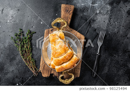 Traditional feta cheese phyllo pastry pie in rustic skillet. Black background. Top view Traditional feta cheese phyllo pastry pie in rustic skillet. Black background. Top view 98125494