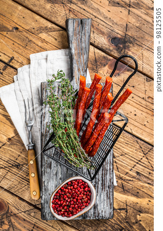 Homemade small thin kabanos sausages in a basket. Wooden background. Top view Homemade small thin kabanos sausages in a basket. Wooden background. Top view 98125505