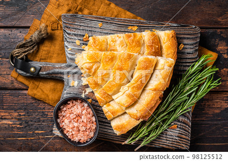 Homemade greek spanakopita pie with organic cheese on wooden board. Wooden background. Top view Homemade greek spanakopita pie with organic cheese on wooden board. Wooden background. Top view 98125512