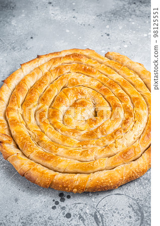 Baked homemade traditional Greek cheese pie on kitchen table. Gray background. Top view Baked homemade traditional Greek cheese pie on kitchen table. Gray background. Top view 98125551
