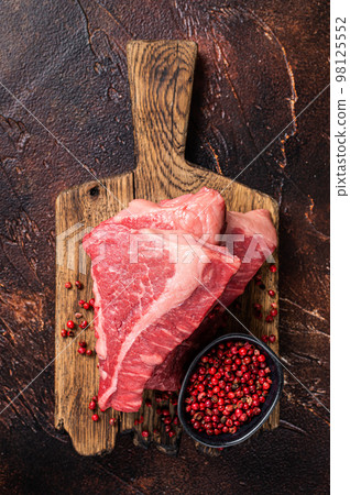 Raw sirloin beef cut, Silverside steak on a wooden board. Dark background. Top view Raw sirloin beef cut, Silverside steak on a wooden board. Dark background. Top view 98125552