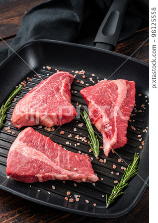 Raw sirloin beef steak, Rump steak cut on a grill skillet. Wooden background. Top view 98125558