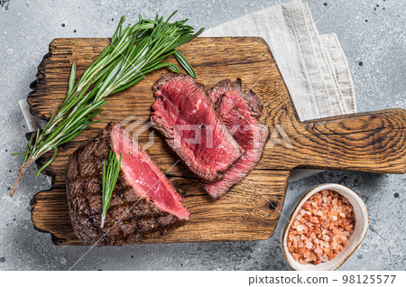 Roasted Rump beef steak sliced on a wooden cutting board. Gray background. Top view 98125577