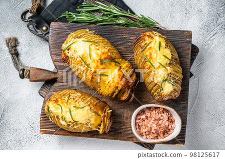 Roasted hasselback potatoes with cheese, garlic, thyme and rosemary. White background. Top view Roasted hasselback potatoes with cheese, garlic, thyme and rosemary. White background. Top view 98125617