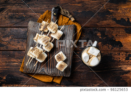 Roasted Marshmallow on the sticks with Cup of coffee on wooden board. Wooden background. Top view 98125653