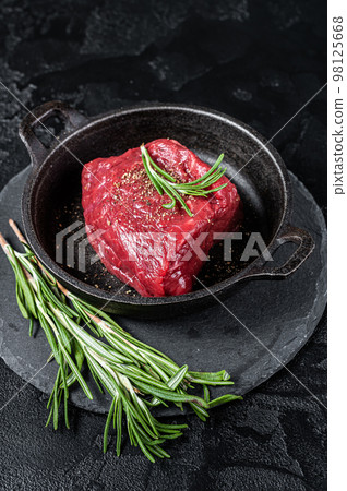 Fresh Raw sirloin rump steak in a skillet with herbs. Black background. Top view 98125668