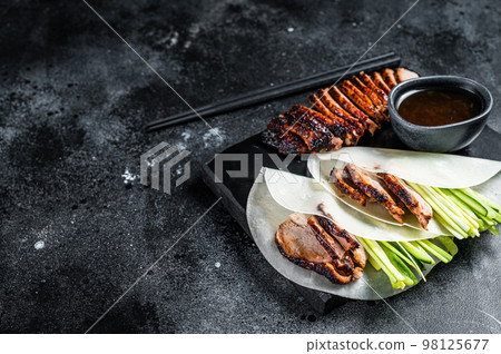 Traditional served Peking Duck with cucumber, green onion, in wheaten chinese pancakes. Black background. Top view. Copy space Traditional served Peking Duck with cucumber, green onion, in wheaten chinese pancakes. Black background. Top view. Copy space 98125677