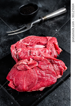 Raw Mutton fillet steaks from leg, uncooked lamb meat. Black background. Top view 98125684