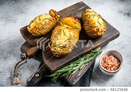 Roasted hasselback potatoes with cheese, garlic, thyme and rosemary. White background. Top view Roasted hasselback potatoes with cheese, garlic, thyme and rosemary. White background. Top view 98125686