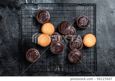 Jaffa Cakes, Cookies covered with dark chocolate and filled with orange marmalade. Black background. Top view 98125687