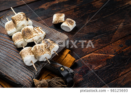 Roasted Marshmallow on the sticks with Cup of coffee on wooden board. Wooden background. Top view. Copy space 98125693