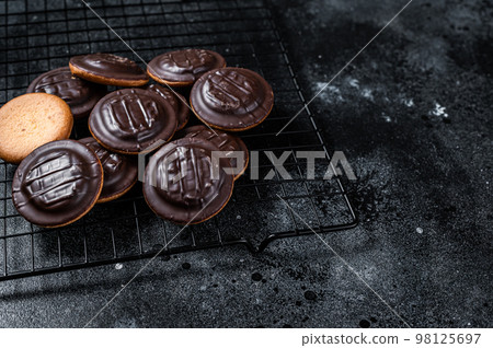 Jaffa Cakes, Cookies covered with dark chocolate and filled with orange marmalade. Black background. Top view. Copy space 98125697