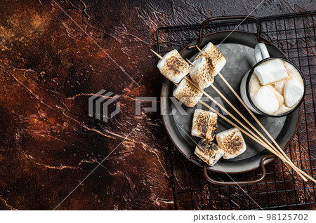 Fried Marshmallow on the sticks with Cup of coffee. Dark background. Top view. Copy space Fried Marshmallow on the sticks with Cup of coffee. Dark background. Top view. Copy space 98125702