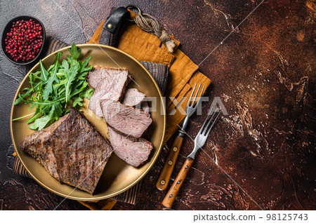 Roast Tri Tip or sirloin bottom beef steak on a plate with arugula. Dark background. Top view. Copy space Roast Tri Tip or sirloin bottom beef steak on a plate with arugula. Dark background. Top view. Copy space 98125743