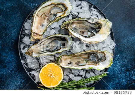 Seafood appetizer - Opened Fresh oysters with lemon and ice. Blue background. Top view 98125753