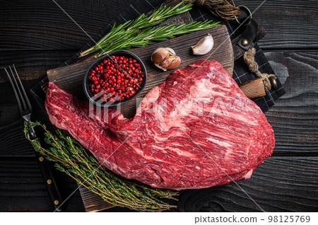 Tri Tip black angus beef steak on cutting board with herbs, raw meat. Black Wooden background. Top view 98125769