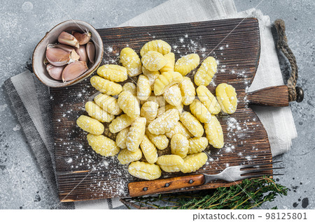 Raw homemade potato gnocchi with fork on wooden cutting board. Gray background. Top view Raw homemade potato gnocchi with fork on wooden cutting board. Gray background. Top view 98125801